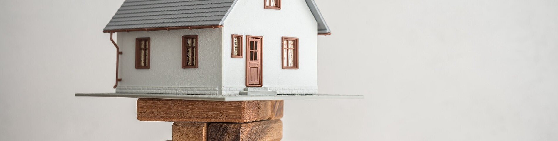 Modern house on wood tower block game white wall background copy space. Mortgage loan for buying home or real estate property, money risk management in financial, foreclosure and bankruptcy concept