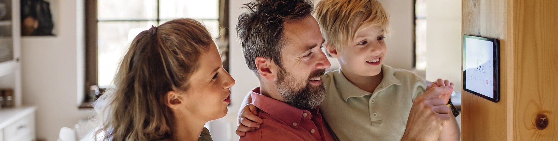 Family looking at smart thermostat, adjusting, lowering heating temperature at home. Concept of sustainable, efficient, and smart technology in home heating and thermostats. Family looking at smart thermostat, adjusting, lowering heating temperature at home. Concept of sustainable, efficient, and smart technology in home heating and thermostats.